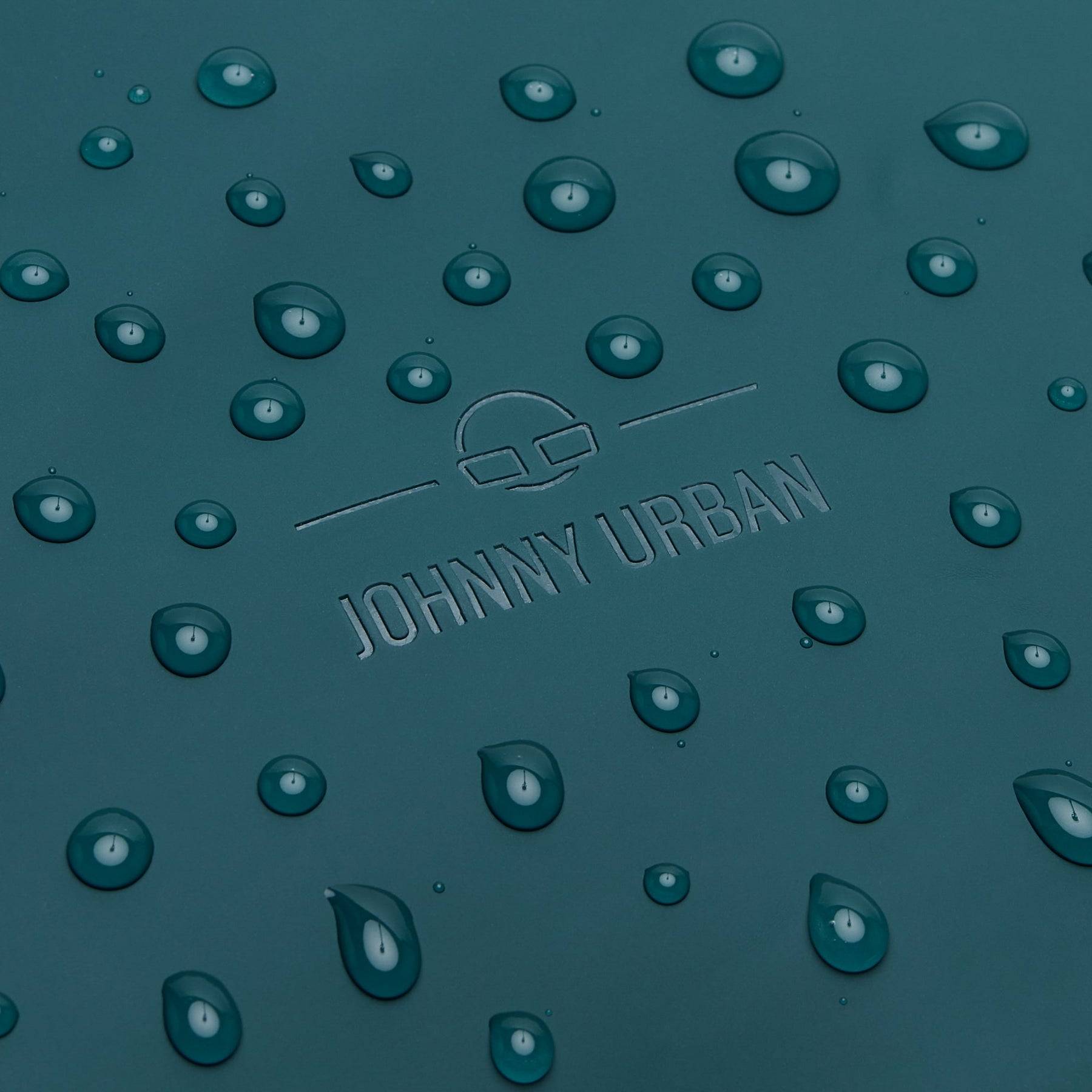 Nahaufnahme des petrolfarbenen Johnny Urban Rolltop Rucksacks 'Henry' mit Wasserperlen auf der Oberfläche
